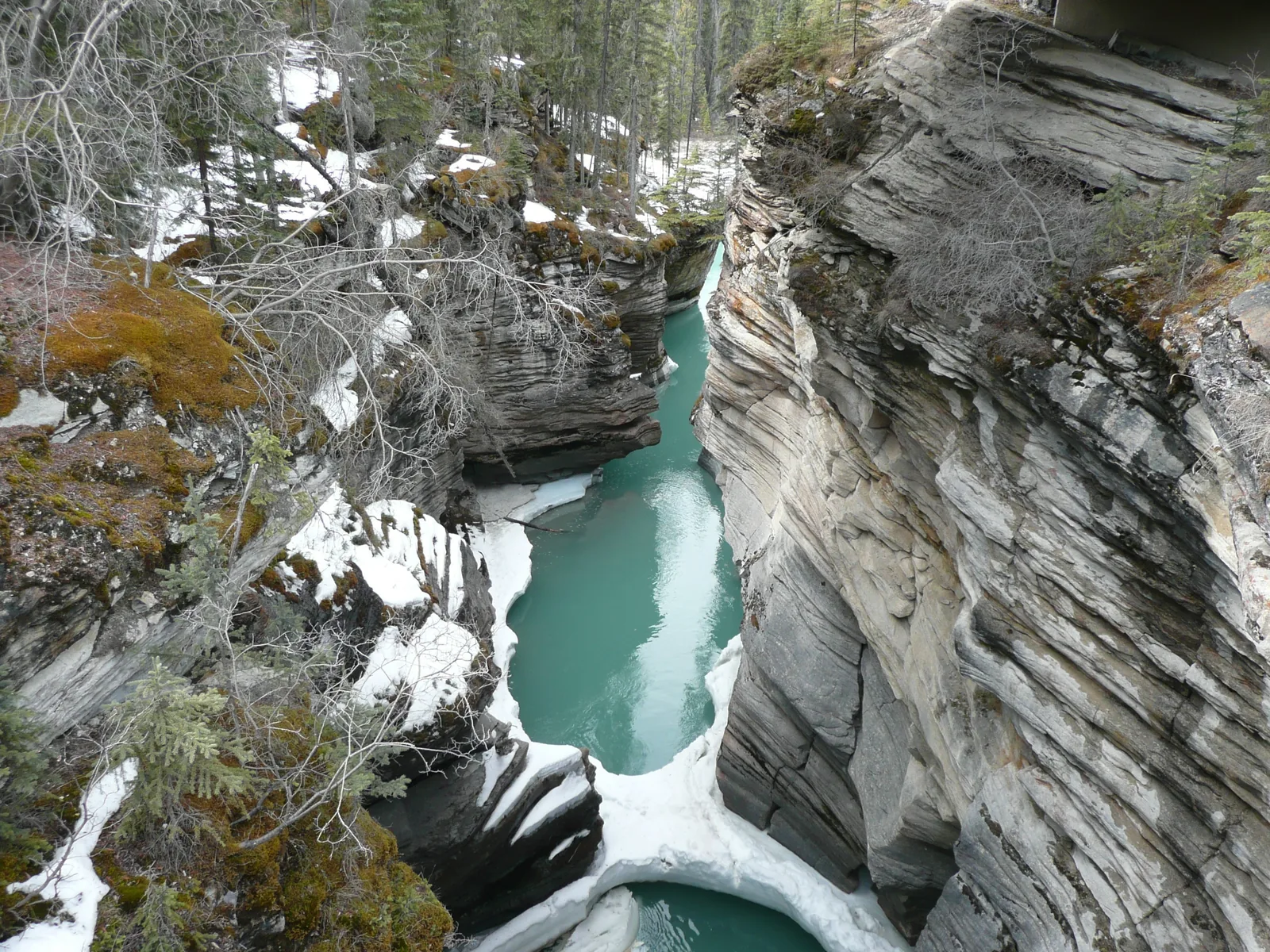 Türkisfarbenes Wasser in der engen Schlucht unter den Athabasca Falls im Jasper-Nationalpark, an den Rändern Schnee