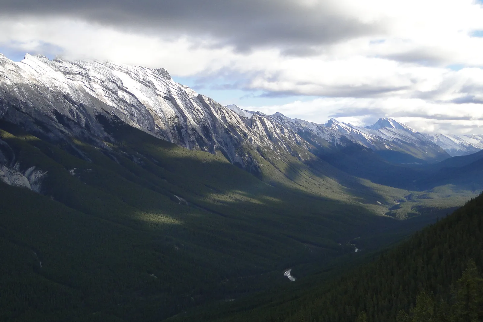 Blick vom Sulphur Mountain in ein breites, bewaldetes Tal mit verschneitem Bergkamm