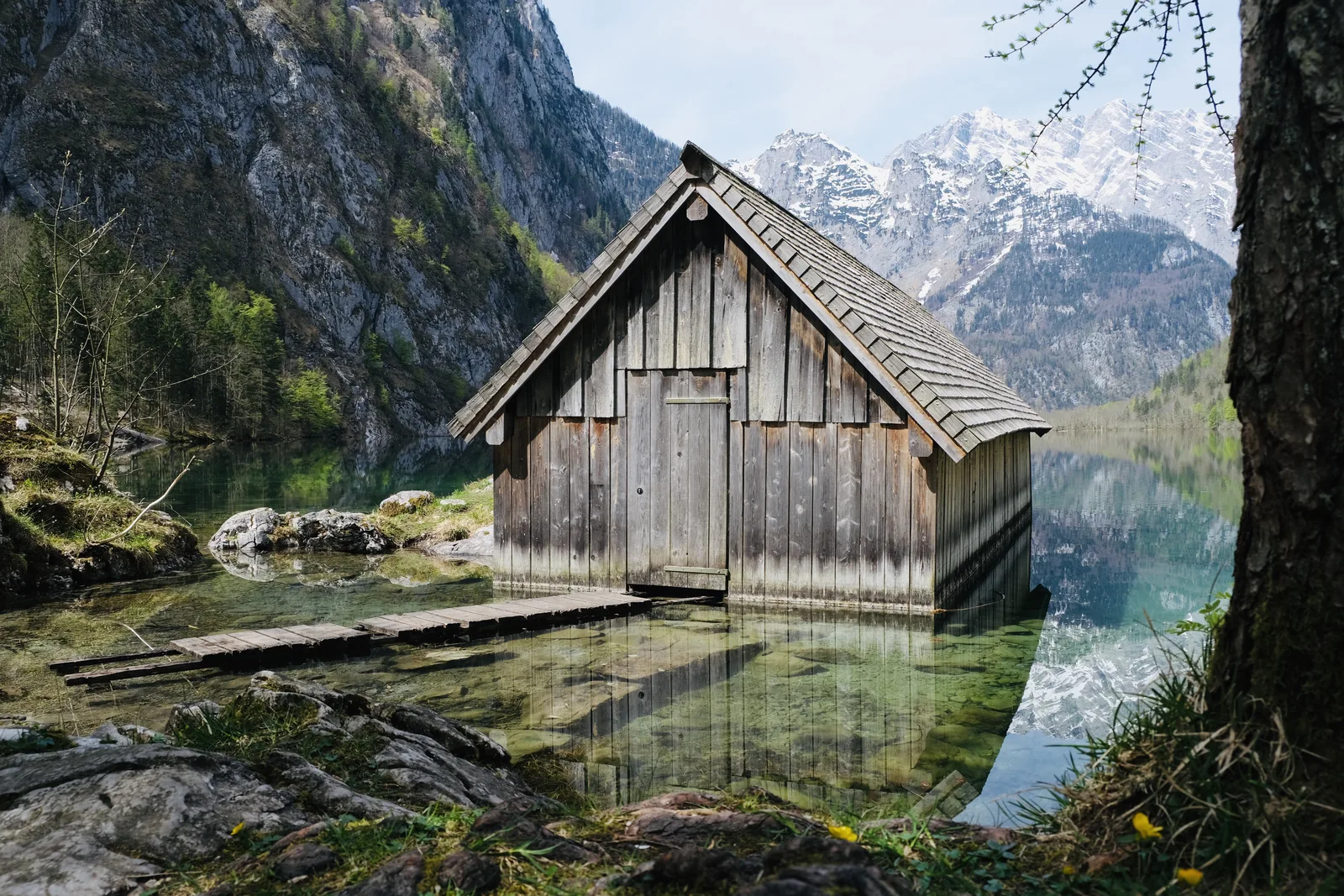Hölzerne Bootshütte an der Fischunkelalm im klaren Wasser des Obersees