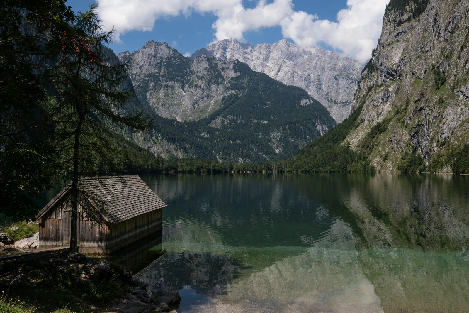 Der Obersee spiegelt die umstehenden Felswände, am Ufer eine hölzerne Bootshütte