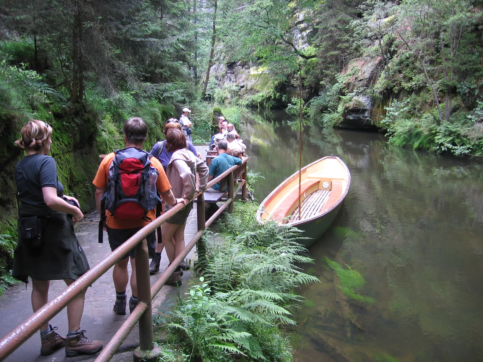 Wanderer warten am Geländer der Wilden Klamm in der Böhmischen Schweiz auf den Kahn, der am Ufer der Kamnitz liegt
