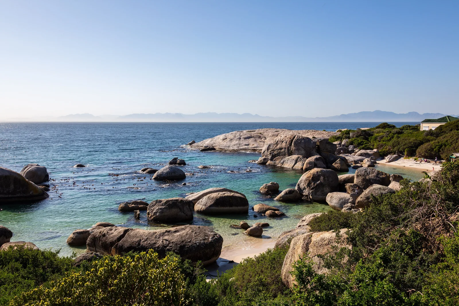 Blick über die Felsbuchten von Boulders Beach mit großen Granitblöcken im türkisfarbenen Wasser der False Bay