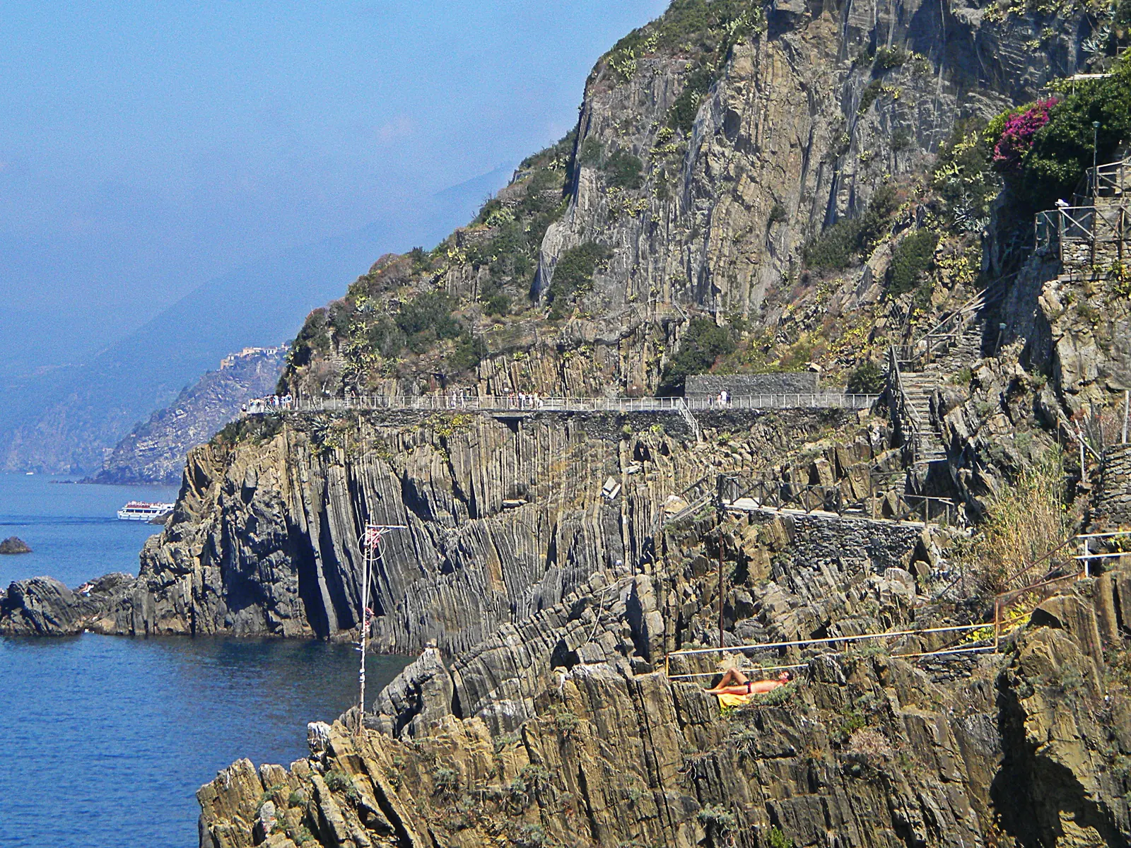 Die Via dell'Amore im Nationalpark Cinque Terre: ein gemauerter Weg mit Geländer an der steilen, geschichteten Felsküste über dem Meer