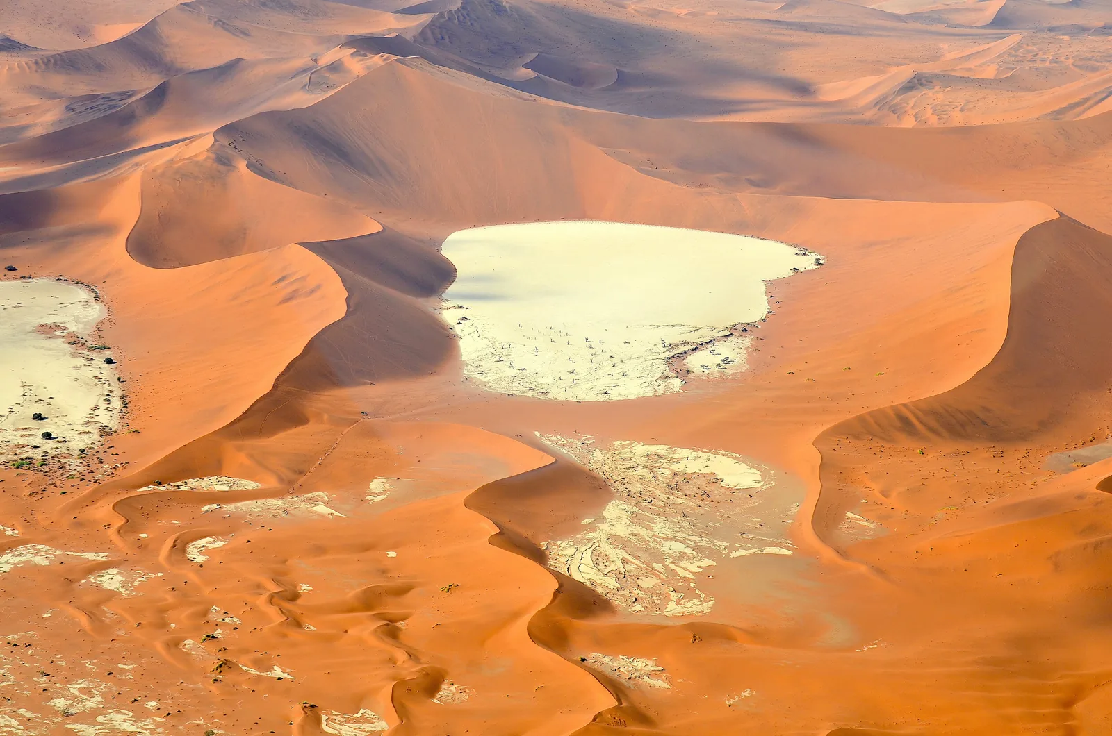Deadvlei im Namib-Naukluft-Park aus der Luft: weiße Tonpfanne mit dunklen Baumpunkten zwischen roten Dünen