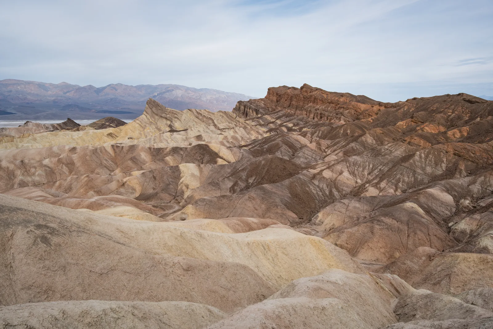 Blick vom Zabriskie Point über zerfurchte helle Badlands, rechts die rotbraunen Wände der Red Cathedral, im Hintergrund das Tal