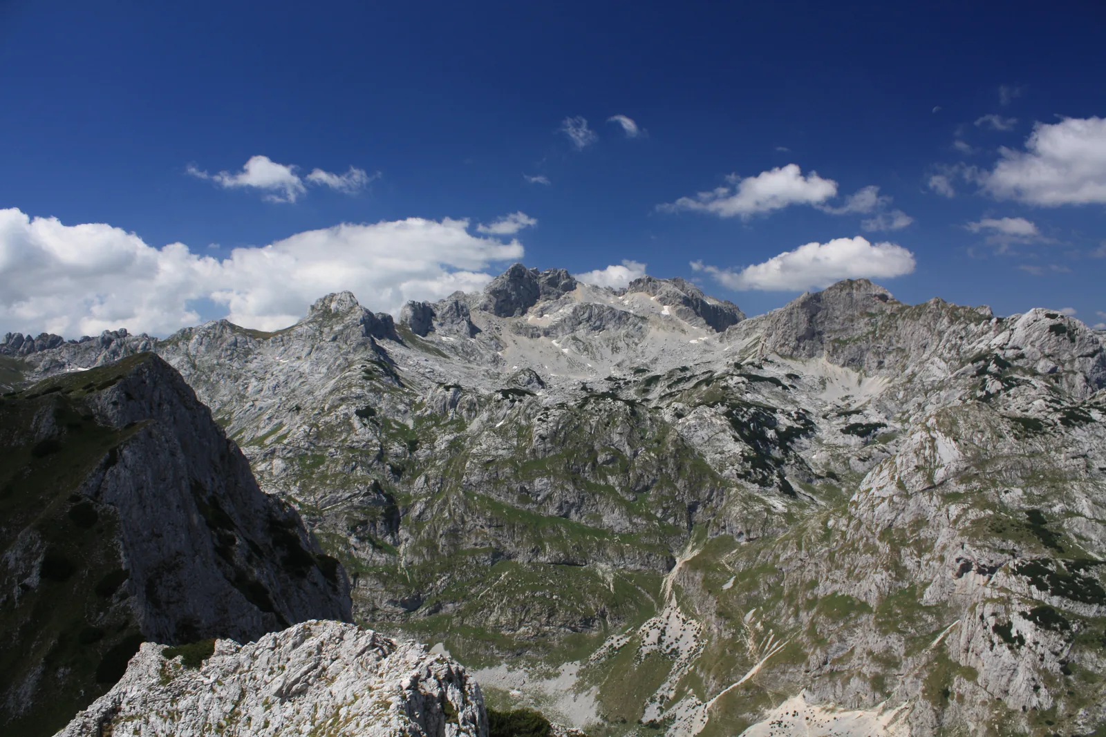 Blick über ein zerklüftetes, helles Kalkgebirge mit schroffen Graten und Mulden unter tiefblauem Himmel