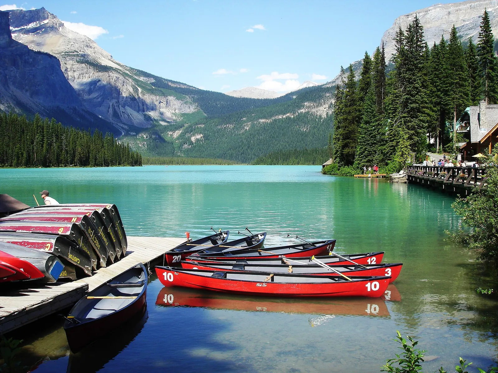 Rote Mietkanus am Steg des Emerald Lake im Yoho-Nationalpark, dahinter Lodge und Berge am grünen Wasser.