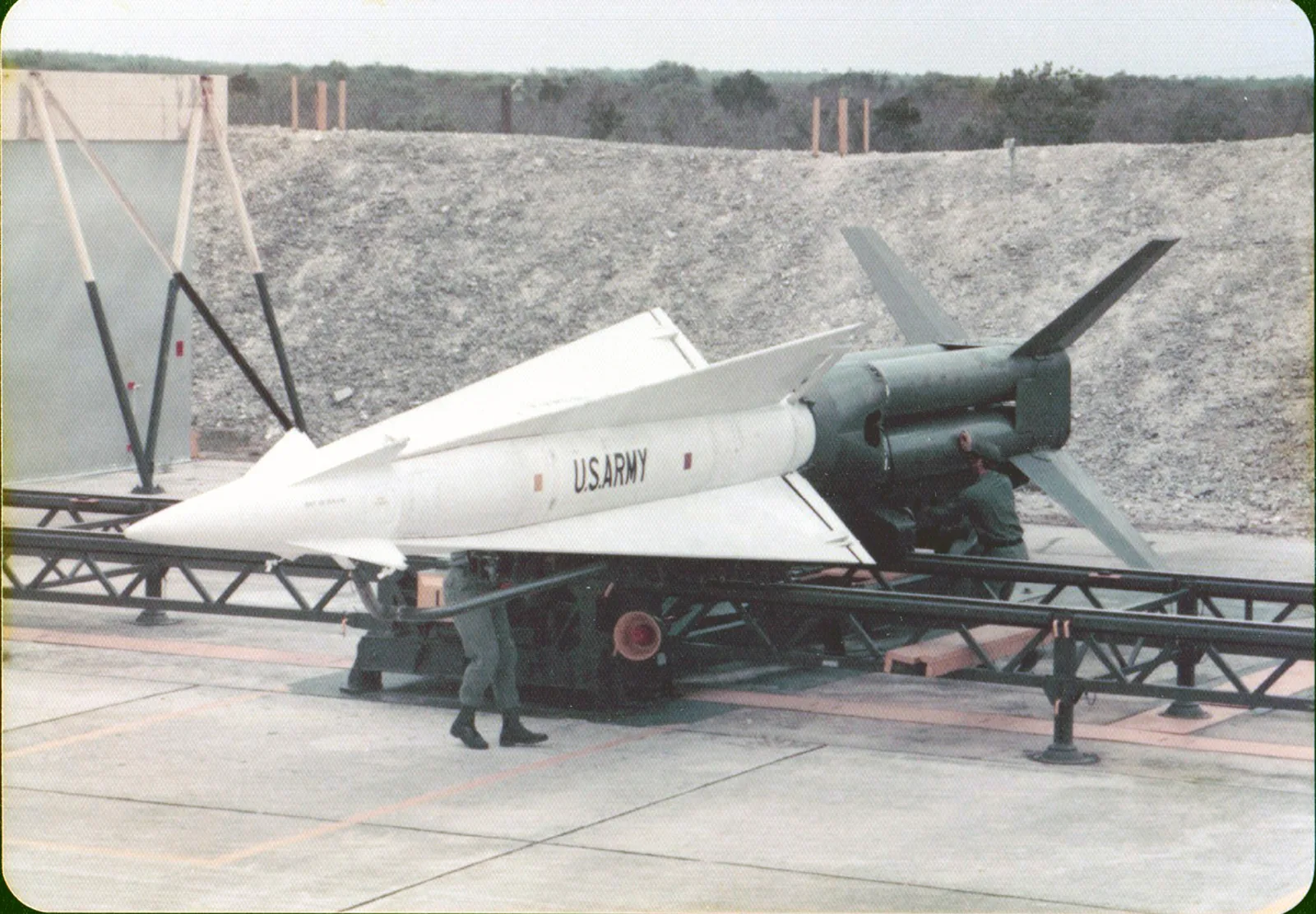 Historisches Farbfoto von 1977: eine weiße Nike-Hercules-Rakete mit US-Army-Schriftzug auf ihrer Startlafette vor einer Raketenhalle