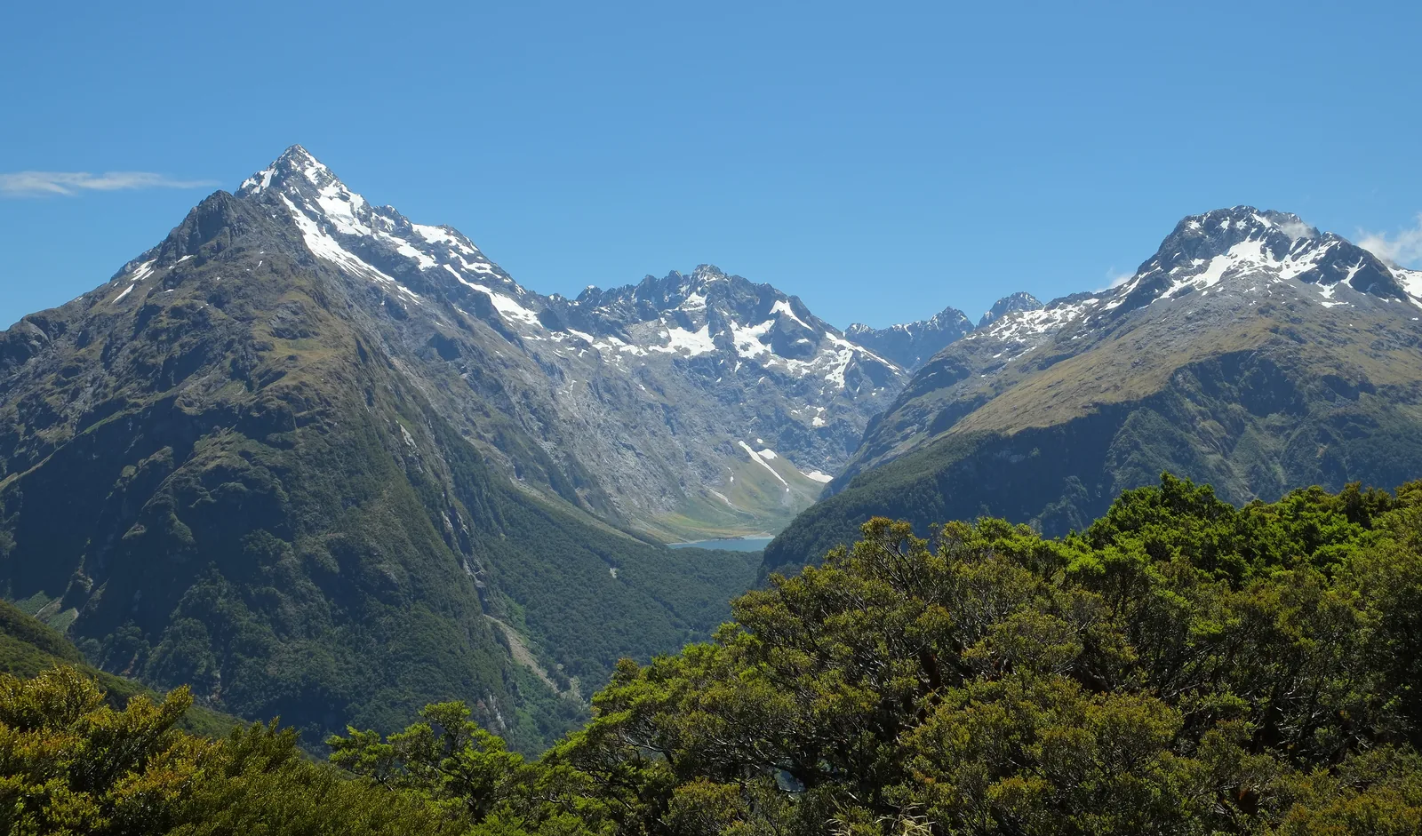 Blick vom Key Summit im Fiordland-Nationalpark auf den schneebedeckten Mount Christina und das Tal zum Lake Marian