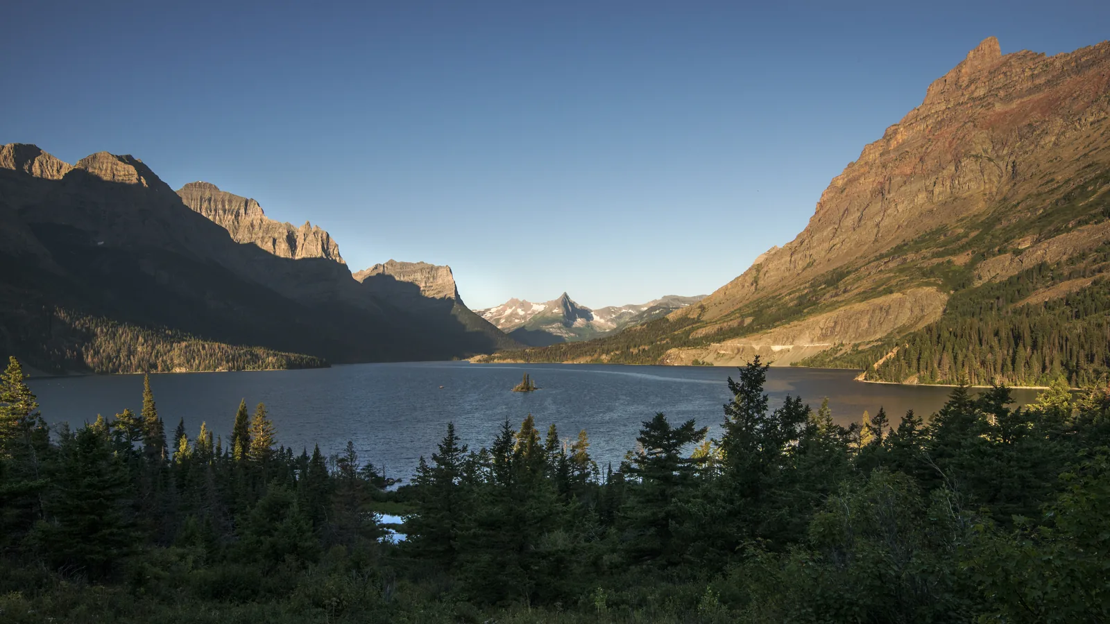 Der St. Mary Lake mit der kleinen bewaldeten Insel Wild Goose Island, umrahmt von steilen Bergflanken im Abendlicht