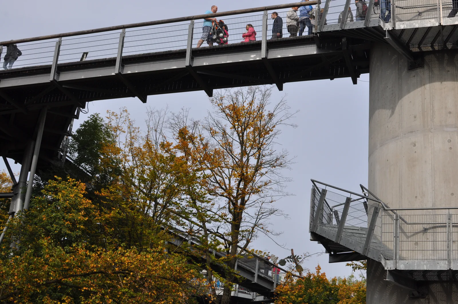 Die Stahlkonstruktion des Baumkronenpfads von unten gesehen, Besucher gehen in Höhe der Baumwipfel