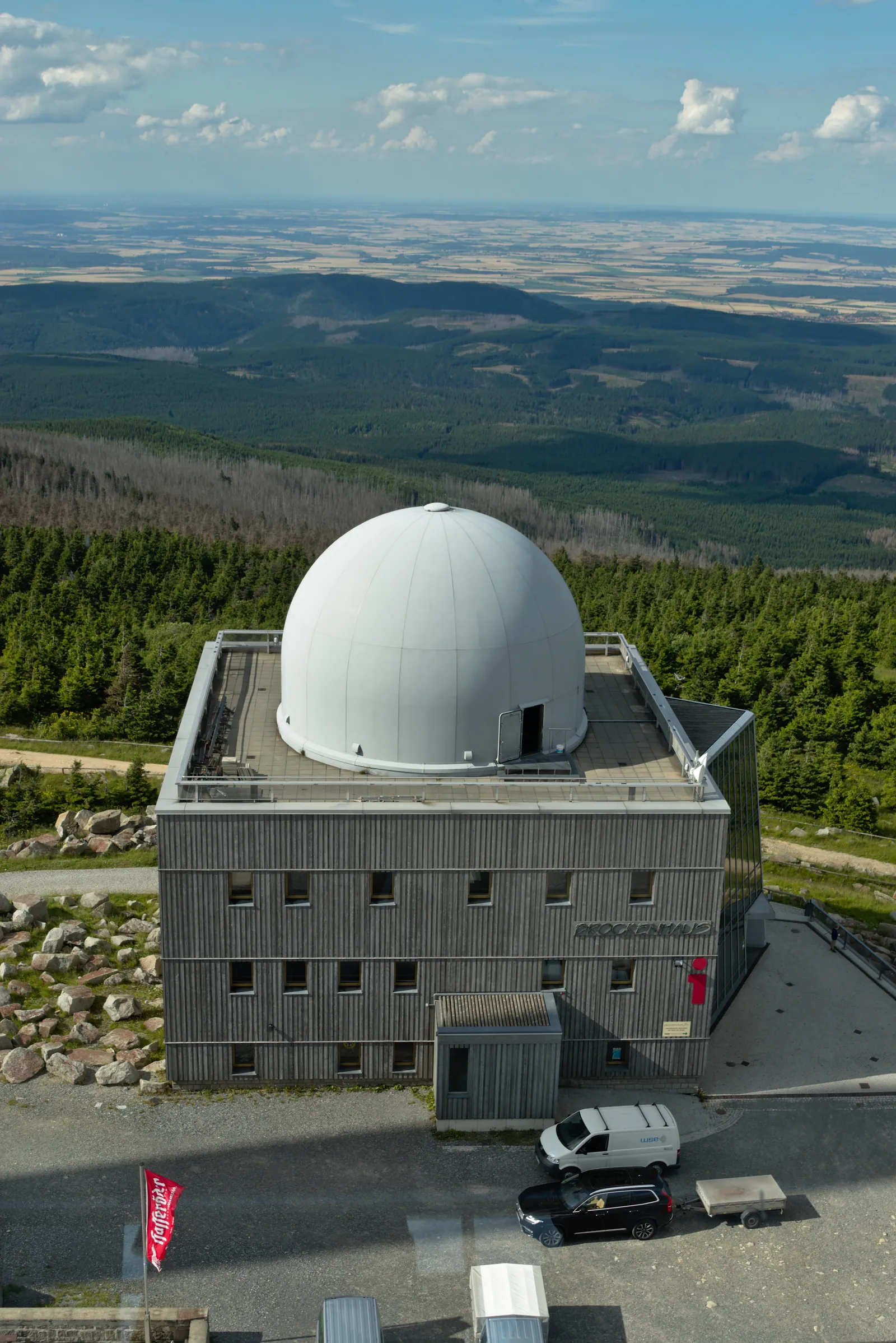 Das Brockenhaus mit seiner weißen Kuppel, dahinter der Blick über den Harz