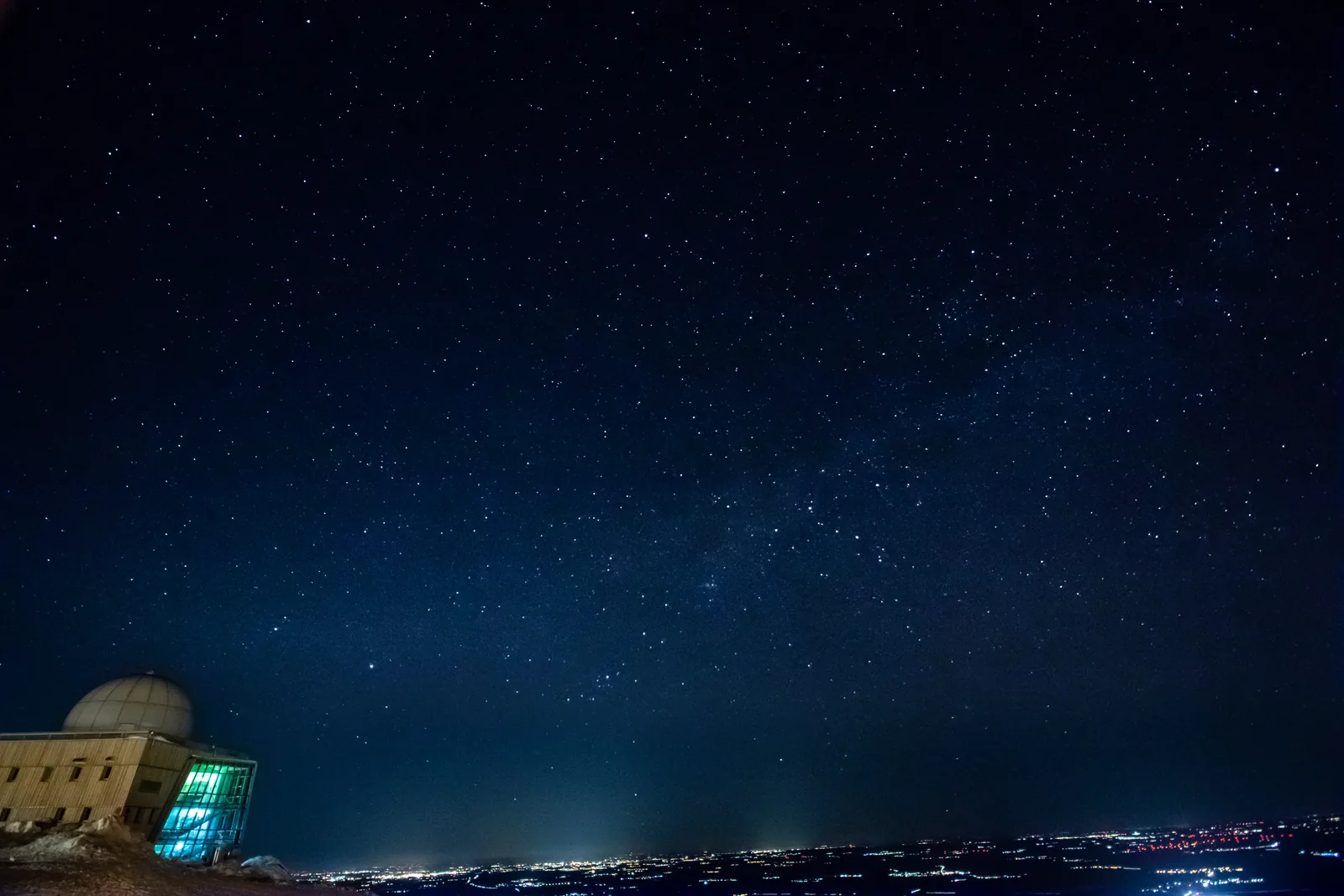 Sternenhimmel über dem Brockengipfel, am Horizont die Lichter der Städte