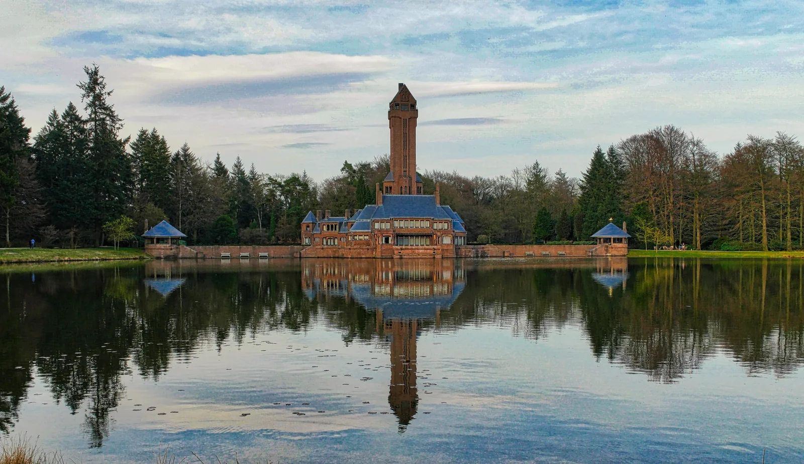 Das Jachthuis Sint Hubertus im Nationalpark De Hoge Veluwe mit seinem Turm, gespiegelt im Teich davor