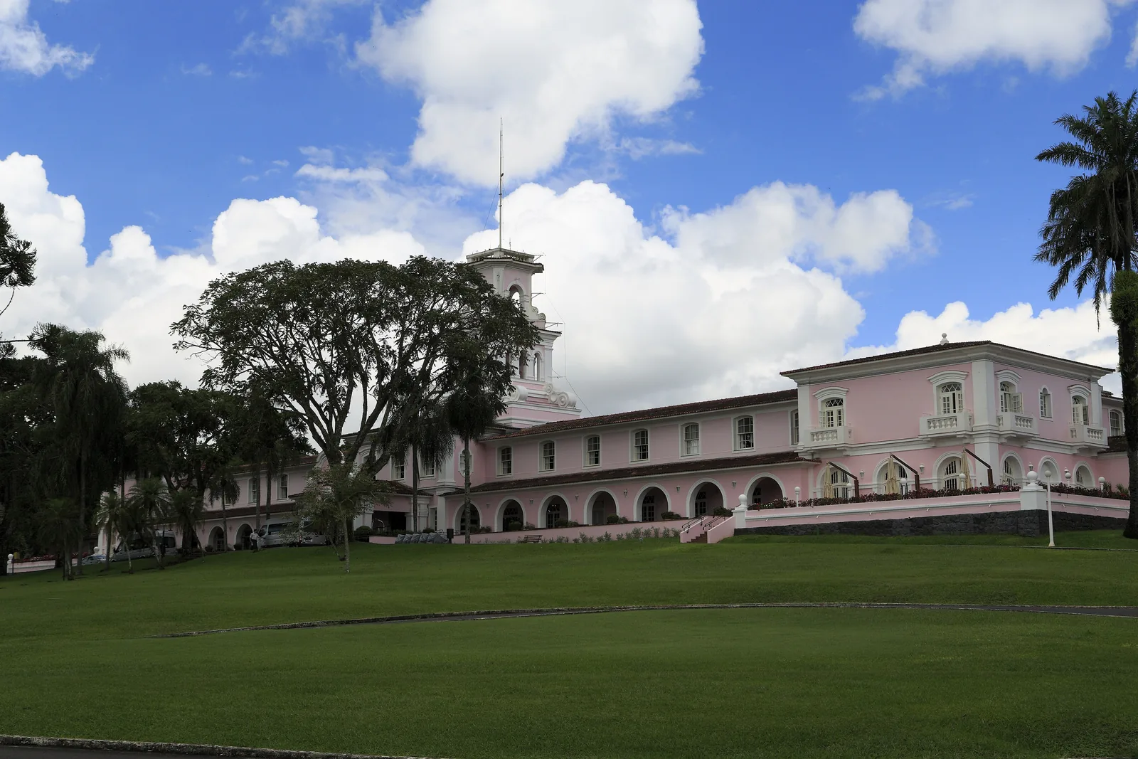 Das rosa Belmond Hotel das Cataratas mit Turm steht hinter einer weiten Rasenfläche im Iguaçu-Nationalpark