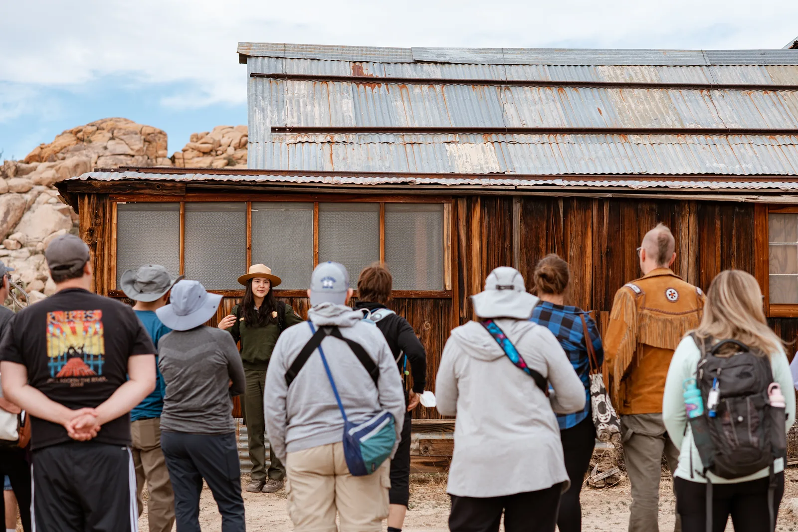Eine Rangerin führt eine Besuchergruppe vor dem hölzernen Hauptgebäude der historischen Keys Ranch