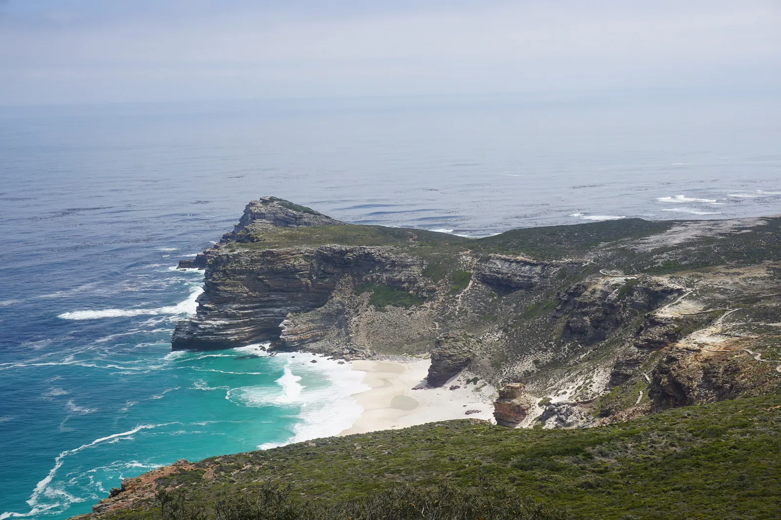 Blick von Cape Point hinunter auf das Kap der Guten Hoffnung mit hellem Sandstrand und Brandung