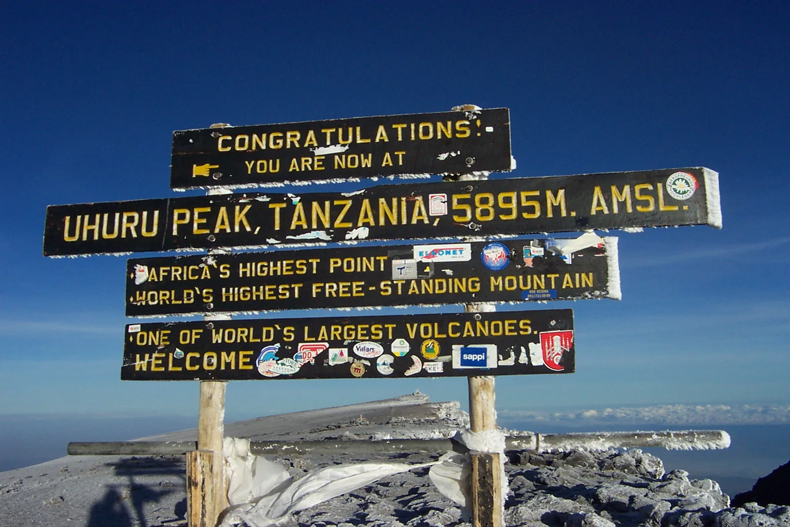 Die Holztafeln am Uhuru Peak im Kilimandscharo-Nationalpark mit der Höhe 5895 m vor tiefblauem Himmel