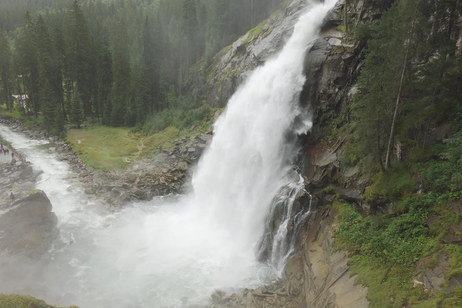 Weißes Wasser der Krimmler Wasserfälle schießt über dunklen Fels in eine Gischtwolke, aufgenommen vom Wasserfallweg