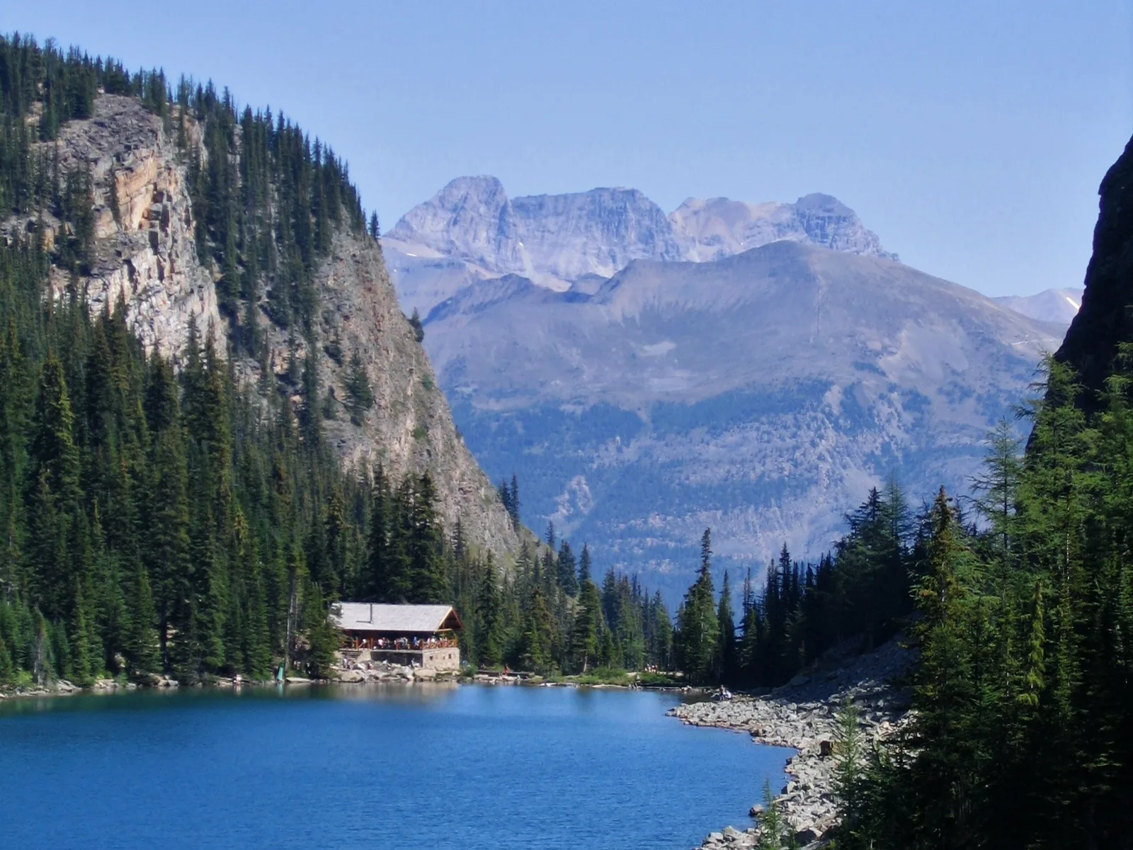 Das Teehaus am Lake Agnes am Ufer eines dunkelblauen Bergsees unter einer Felswand