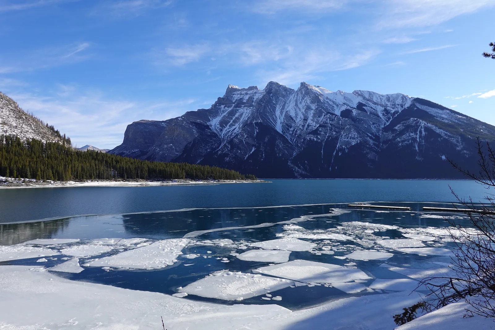 Lake Minnewanka im Banff-Nationalpark im Winter: Eisschollen auf dunkelblauem Wasser, dahinter Mount Girouard und Mount Inglismaldie.