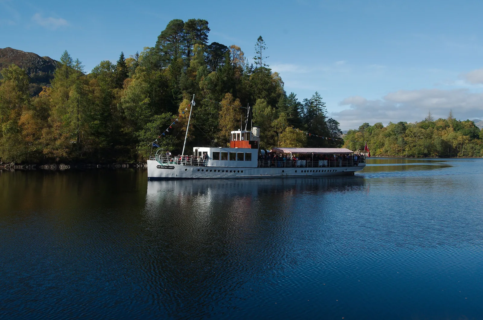 Der Dampfer Sir Walter Scott auf dem Loch Katrine im Loch-Lomond-and-The-Trossachs-Nationalpark vor bewaldeten Ufern