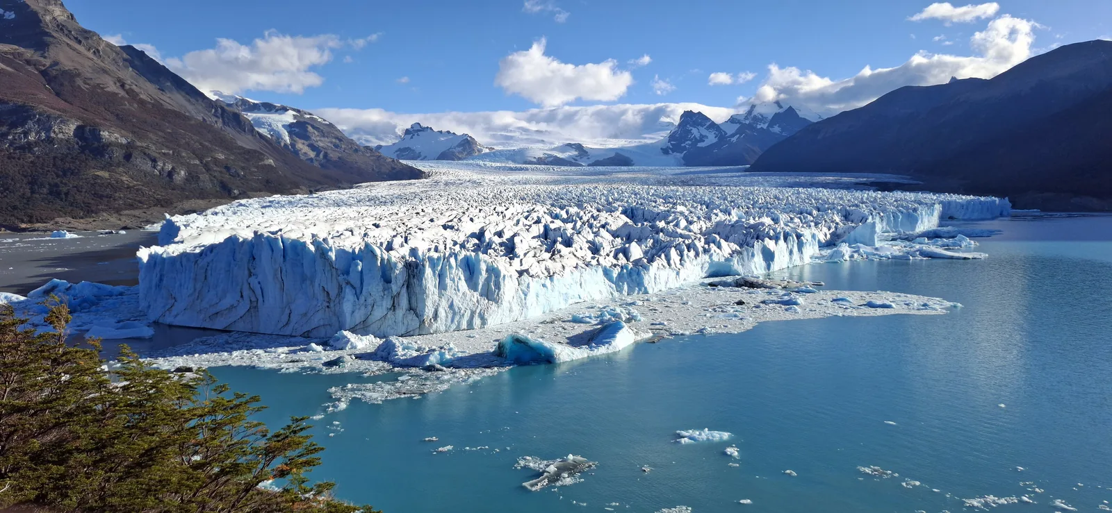Der Perito-Moreno-Gletscher im Nationalpark Los Glaciares, von den Pasarelas aus gesehen: eine weiße Eisfront über dem Lago Argentino, dahinter verschneite Berge