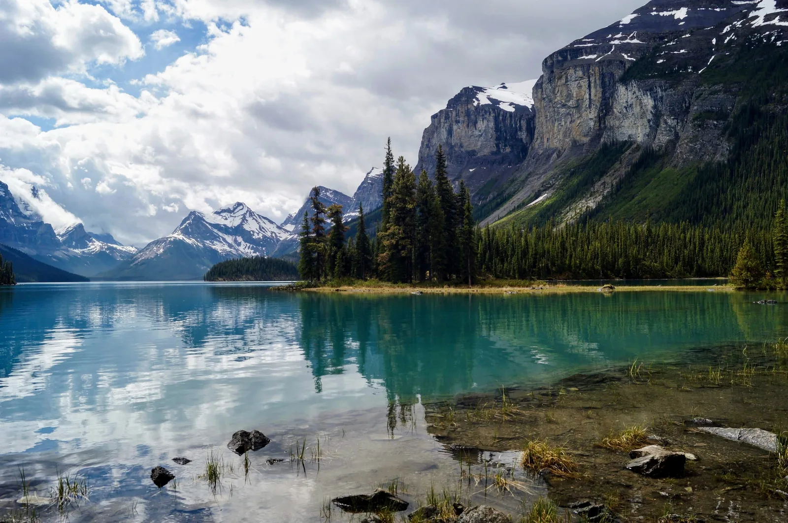 Spirit Island spiegelt sich im ruhigen Wasser des Maligne Lake vor Felswänden