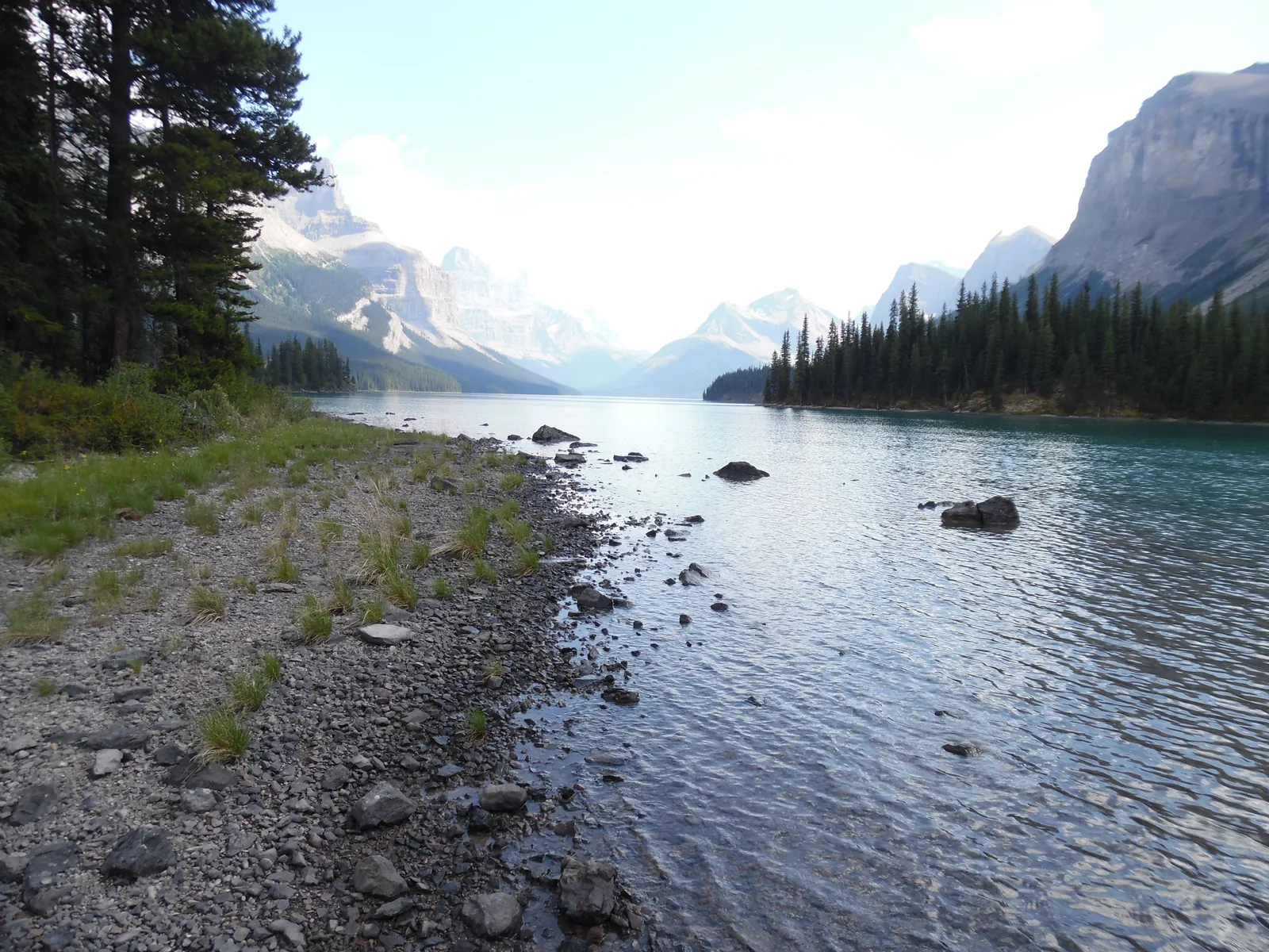 Kiesiges Ufer des Maligne Lake, der See zieht sich zwischen Bergen nach Süden