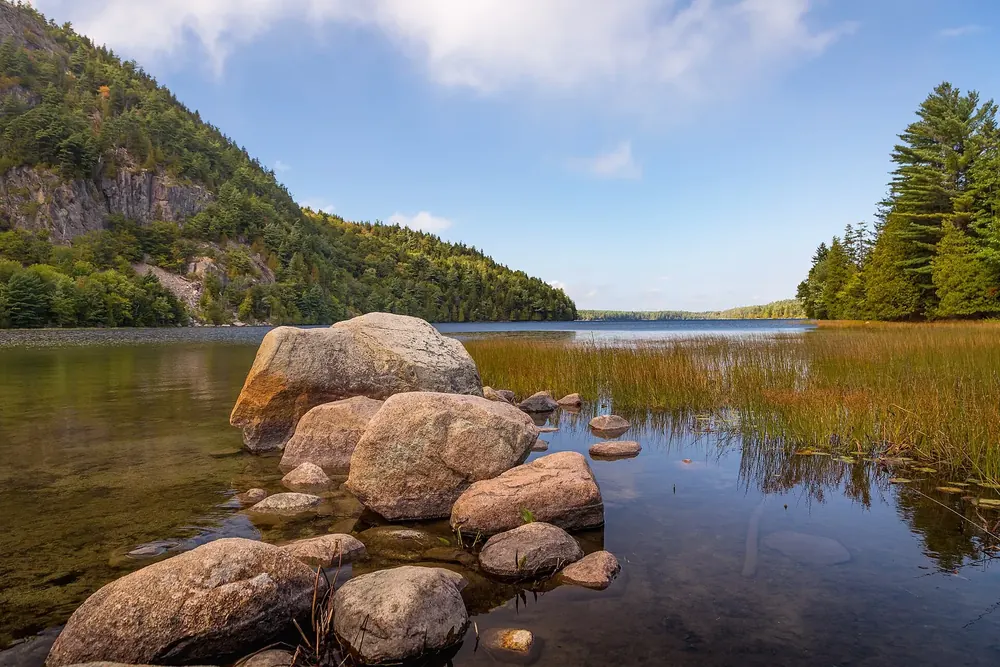 Echo Lake vom Badestrand aus: Granitblöcke und Schilf im klaren Wasser, links eine bewaldete Felswand