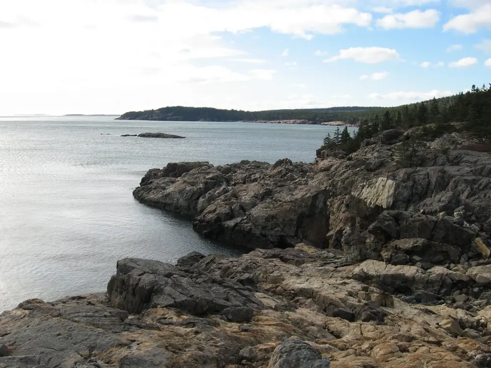 Felsige Granitküste von Great Head, Blick nach Westen über das Meer zu bewaldeten Landzungen