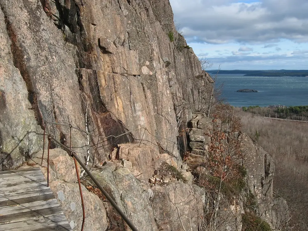 Precipice Trail an der Ostwand des Champlain Mountain: Holzstufen und Eisengeländer am rötlichen Granitfels