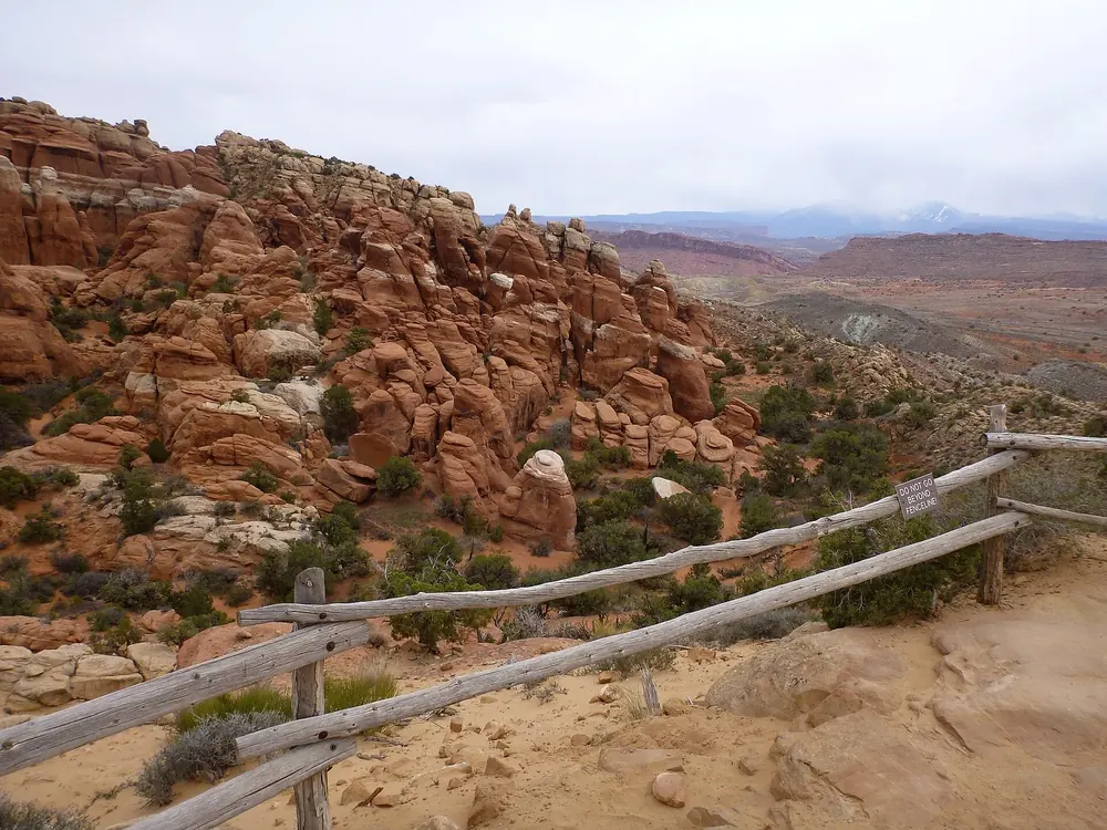 Blick vom Aussichtspunkt über das Labyrinth rötlicher Sandsteinfinnen im Fiery Furnace, vorn ein Holzzaun
