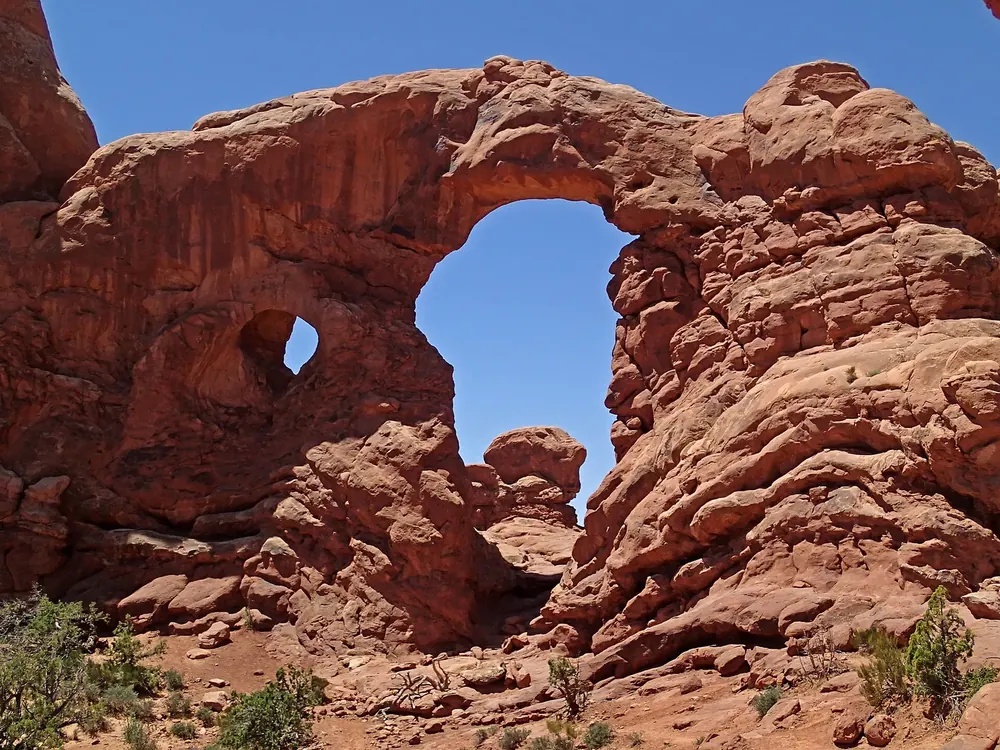 Turret Arch: Sandsteinbogen mit großem und kleinem Fenster, daneben ein turmartiger Felspfeiler unter blauem Himmel