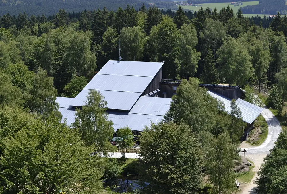 Besucherzentrum Hans-Eisenmann-Haus von oben: großes Gebäude mit hellem Dach inmitten von dichtem Mischwald