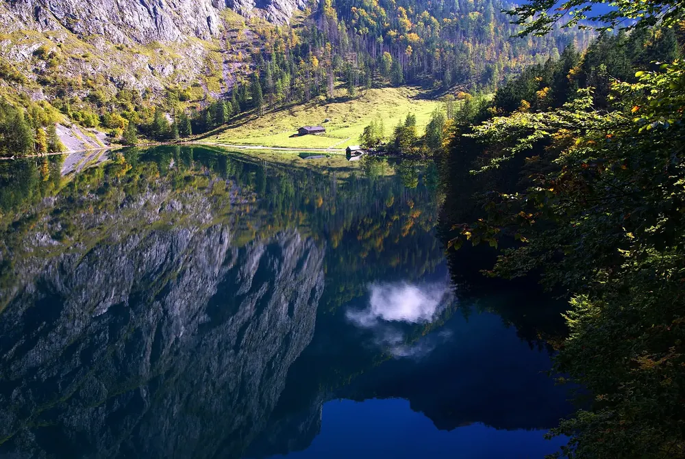 Obersee mit Spiegelung der Felswände, am Ende des Sees die Almwiese der Fischunkelalm mit Hütten