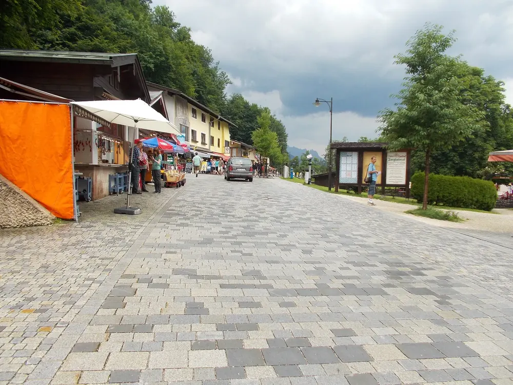 Seestraße zum Königssee nahe dem Parkplatz: gepflasterte Promenade mit Andenkenläden, Bäumen und Laternen
