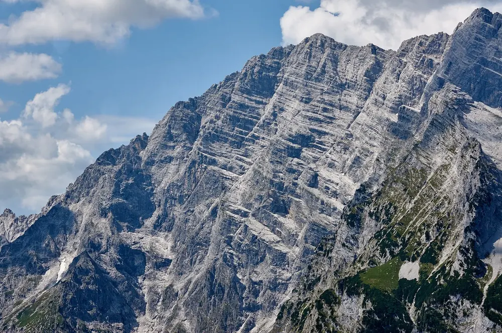 Watzmann-Ostwand mit der Südspitze: gewaltige, gebänderte Kalkfelswand unter Quellwolken