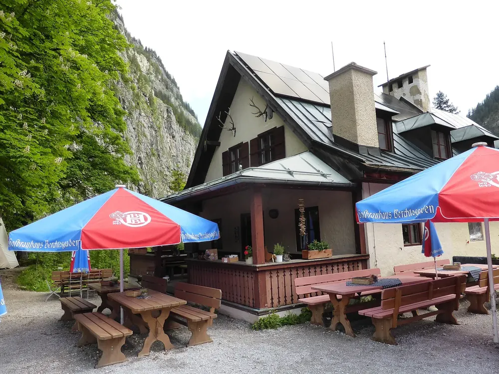 Berggasthof Wimbachschloss, eine ehemalige Jagdhütte im Wimbachtal, mit Biergarten und Sonnenschirmen vor einer Felswand