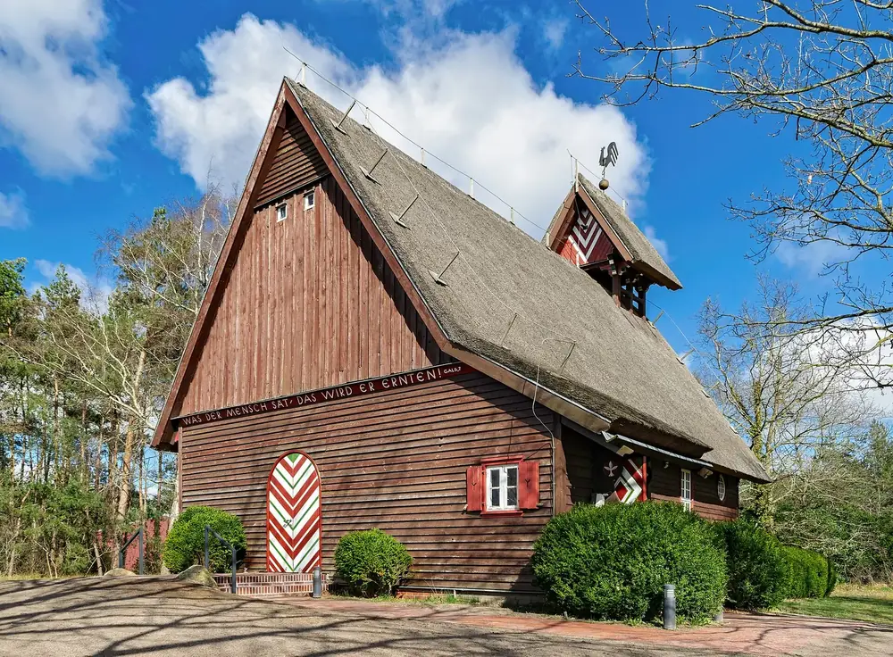 Fischerkirche in Born a. Darß: braune Holzkirche mit steilem Dach und kleinem Glockenturm zwischen Bäumen