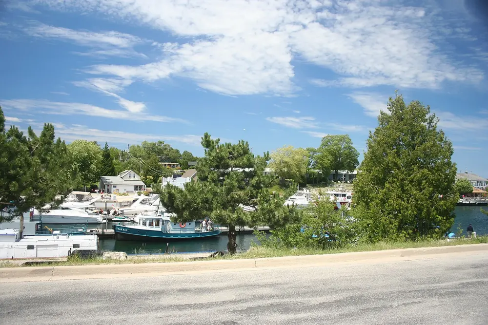 Hafen von Tobermory mit Booten und Anlegern, gesäumt von Bäumen und Häusern unter blauem Himmel