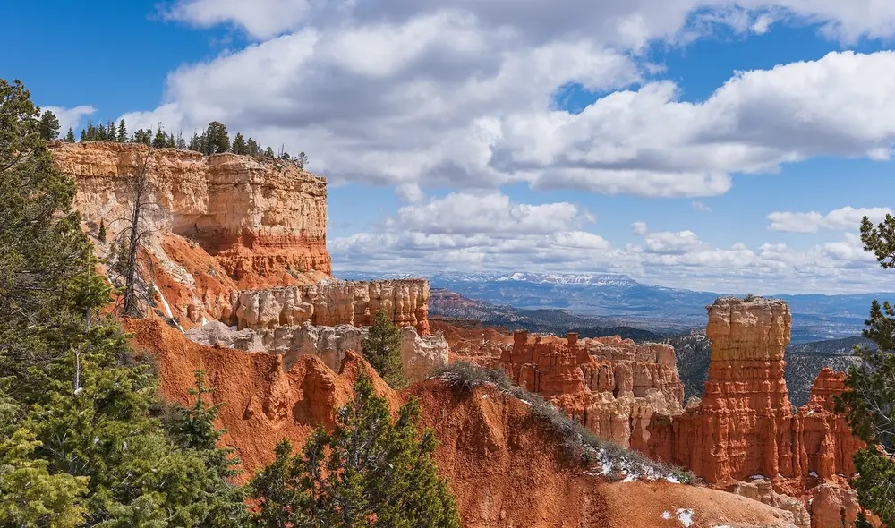 Blick vom Agua Canyon Overlook auf Felsklippen und Hoodoos mit Neuschnee, am Horizont verschneite Berge