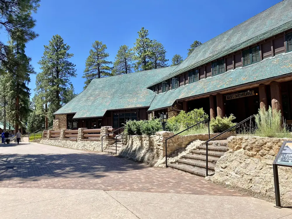 Bryce Canyon Lodge: rustikales Gebäude aus Naturstein und Holz mit grünem Schindeldach, davor Treppe und Kiefern