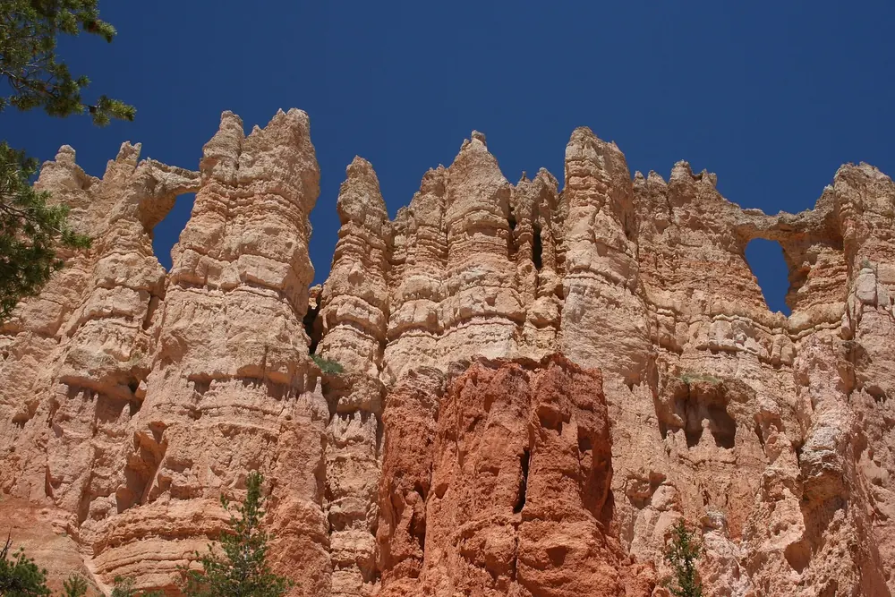 Wall of Windows: zerklüftete Felsrippe aus rötlichem Kalkstein mit mehreren Fensterbögen vor tiefblauem Himmel