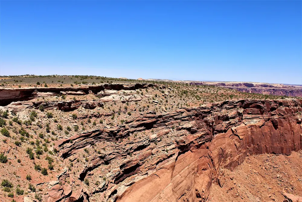Blick vom Buck Canyon Overlook über rote Sandsteinstufen und Canyonränder bis zum weiten Horizont