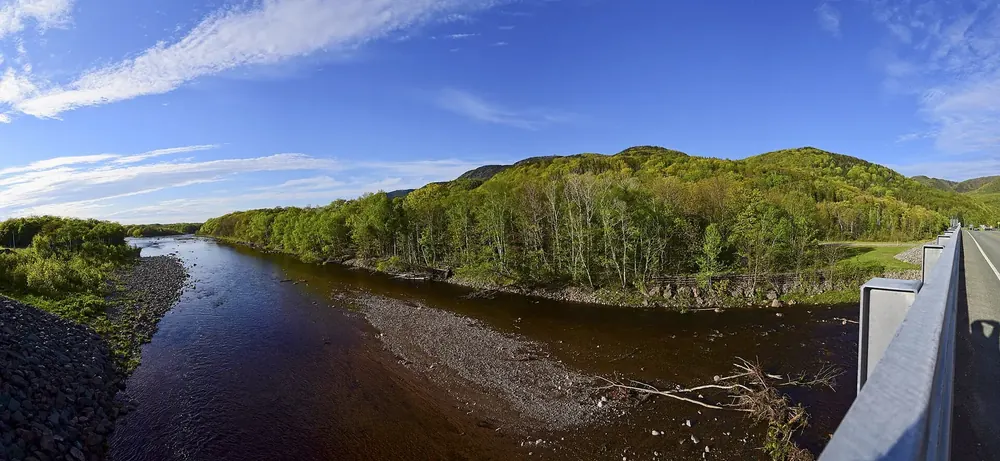 Chéticamp River und Parkeingang des Cape-Breton-Highlands-Nationalparks von der Brücke, bewaldete Hügel