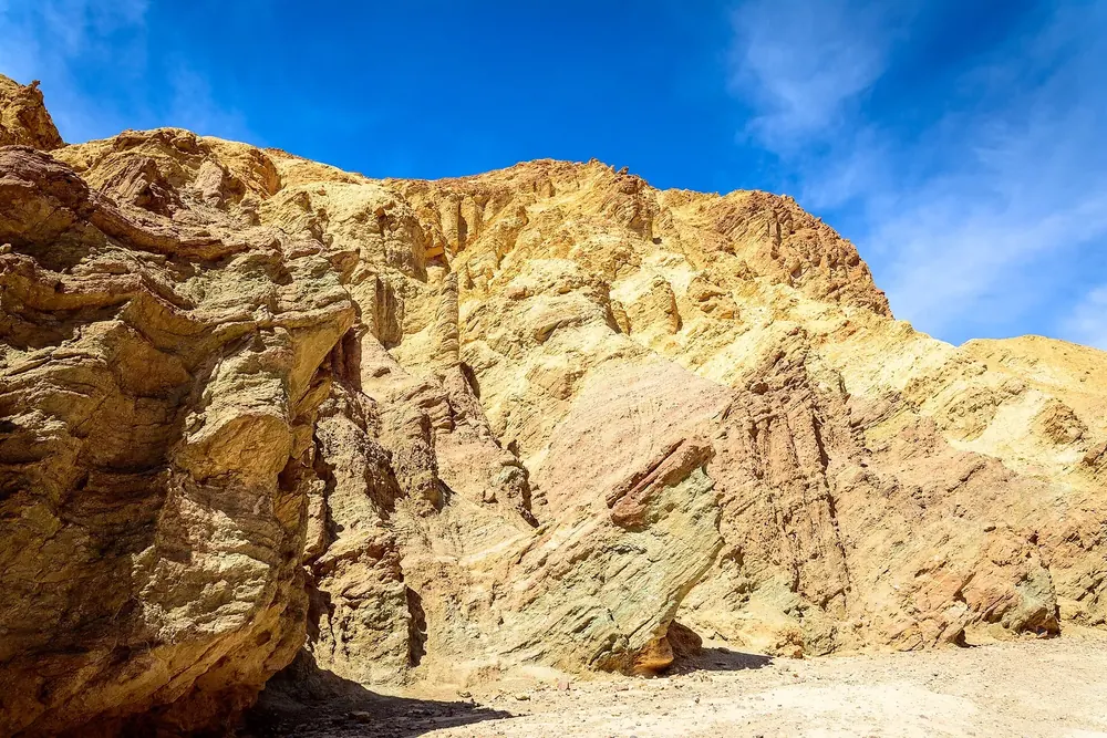 Golden Canyon: leuchtend gelbe, erodierte Felswände unter tiefblauem Himmel mit Schleierwolken