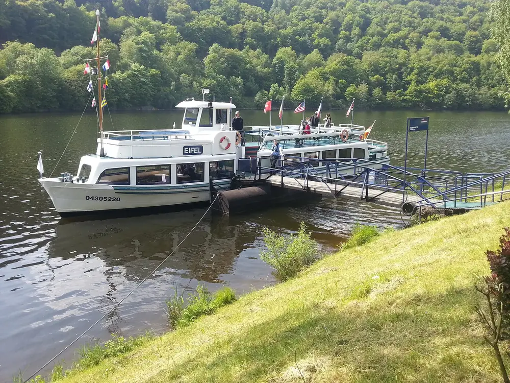 Fahrgastschiff Eifel am Anleger in Einruhr am Obersee, dahinter bewaldete Hänge