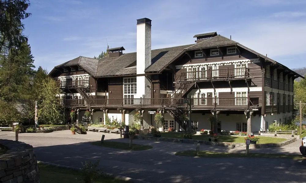 Lake McDonald Lodge: historisches Holzgebäude im Chalet-Stil mit Balkonen und hohem Steinkamin zwischen Bäumen