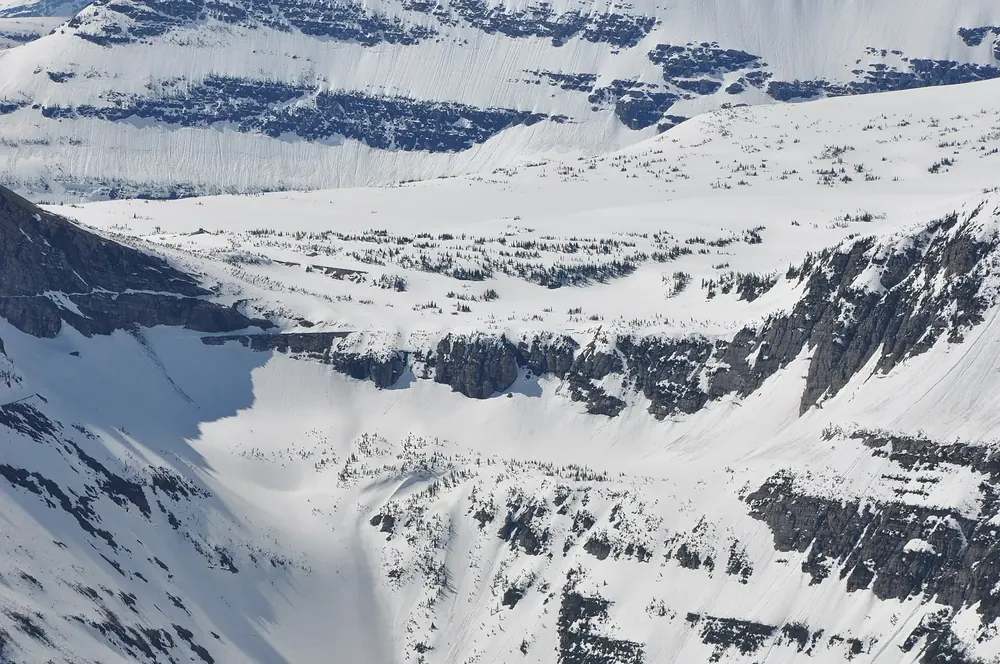 Oberlin Bend im Frühjahr: tief verschneite Berghänge mit Felsbändern über dem Tal an der Going-to-the-Sun Road